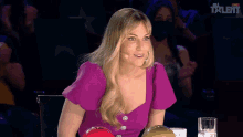a woman in a purple top is sitting in front of a sign that says " talent "