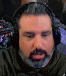 a man with a beard wearing headphones is looking at the camera