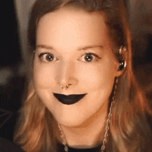 the woman is wearing black lipstick and a nose ring .