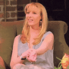 a woman with blonde hair is sitting in a chair with her arm outstretched