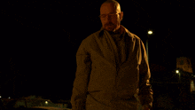 a man with glasses and a beard is smoking a cigarette in the dark