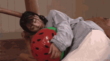 a woman is laying on the floor holding a strawberry shaped inflatable ball