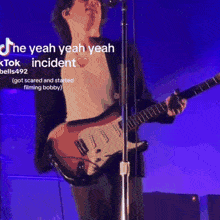 a man singing into a microphone while playing a guitar with a purple background