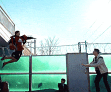 a man holding a basketball is jumping over a fence
