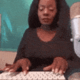 a woman is typing on a keyboard with her eyes closed .