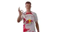 a man wearing a white red bull shirt giving an ok sign
